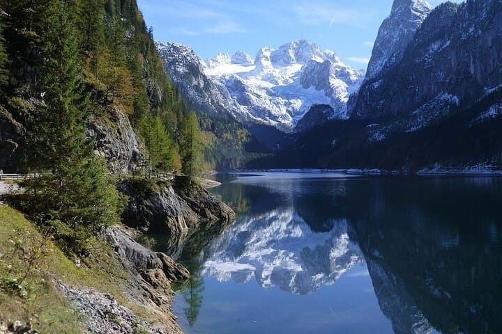 Majestic Dachstein: Feel the raw power of the Austrian Alps as you stand before the rugged, snow-capped peaks towering over the crystal-clear water.