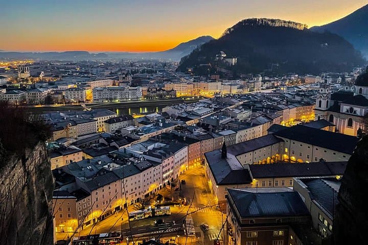 Experience Salzburg’s Old Town as the sun sets, casting a warm glow over the city and its mountains.
