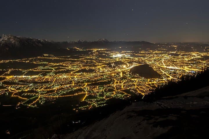 Stunning night views from Gaisberg, overlooking the sparkling city of Salzburg with the majestic Bavarian Alps in the background. A perfect blend of city lights and mountain silhouettes.