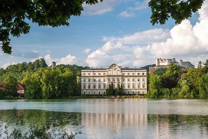 Admire the stunning view of Schloss Leopoldskron from across the Lake, with the majestic Hohensalzburg Fortress rising in the background—a picture-perfect scene from ‘The Sound of Music.
