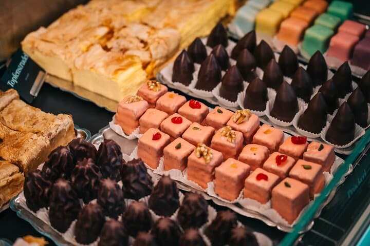 Colorful bite-size Viennese desserts on display at a historic patisserie.