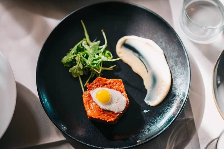 Beautifully plated beef tartare with quail egg and salad, one of the refined pairings on the menu.