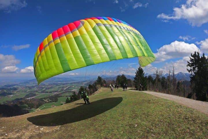Tandem paragliding takeoff from the wide meadow on Gaisberg Mountain near Salzburg. Safe launch area with panoramic alpine views and professional flight preparation.