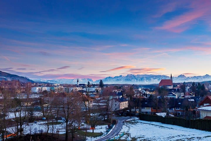 Aerial view of Oberndorf with the majestic Alps in the background, capturing the town’s charming winter landscape near Salzburg.